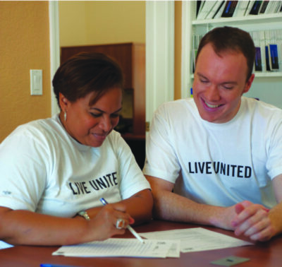 black woman and white man looking over paperwork together, wearing volunteer shirts