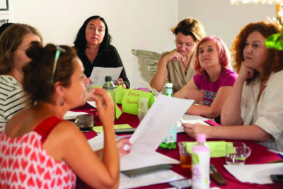 women sitting around table with notebooks as they talk