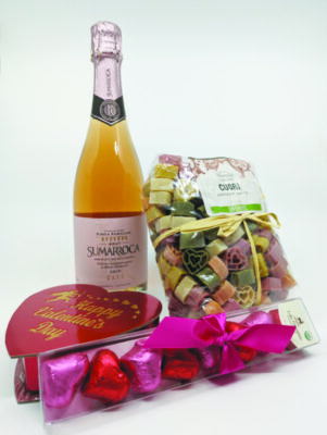 bottle of wine surrounded by Valentine's chocolates and pack of heart shaped pasta