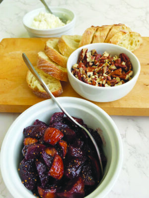 bowl of figs, bowl of walnuts on cutting board beside slices of bread
