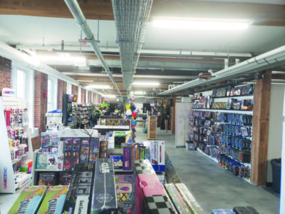 games, comics, and collectibles displayed in shop in large warehouse space with brick walls and cement floor