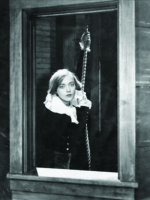 film still from old black and white silent movie showing woman holding rope