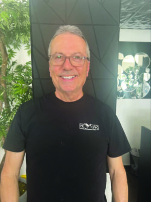 older man, smiling, wearing glasses standing in restauraunt