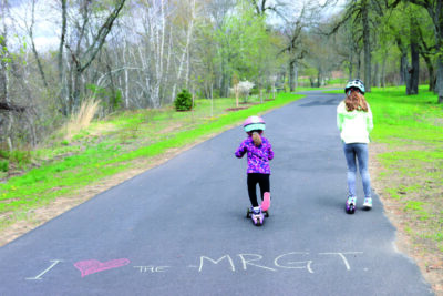 2 girls on scooters on paved path, chalked words on pavement I heart symbol MRGT