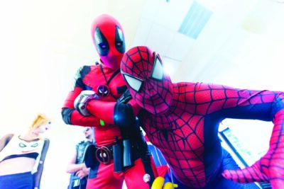 cosplayers dressed as Deadpool and Spiderman posing - Deadpool with arms crossed, Spiderman leaning down toward camera