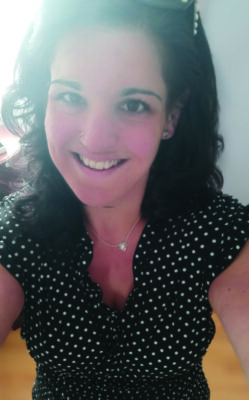 selfie o young woman with dark hair wearing polka dot shirt, smiling