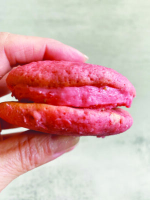 fingers holding pink colored whoopie pie