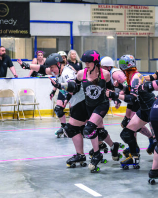 roller derby players from 2 teams crowded on rink as they skate around each other