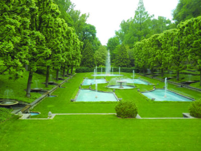 lawn lined with trees, rectangular pools with fountains in the middle