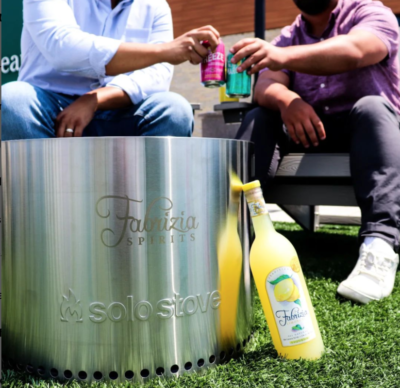 3 men shown from neck down, sitting outside with metal bucket and bottles of limoncello