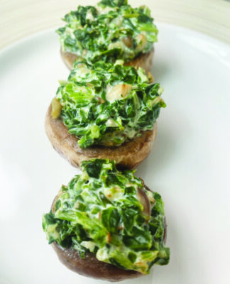 3 white mushroom heads upside down, stuffed with spinach and cheese, in row on plate
