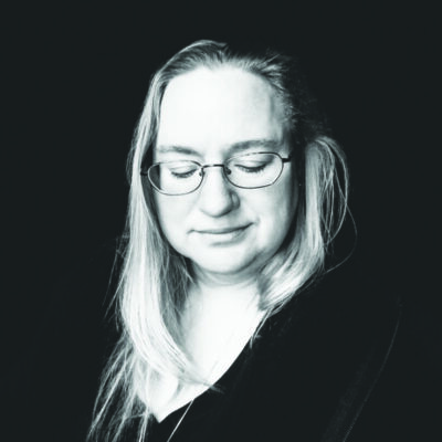 headshot of woman wearing glasses, with long, black and white photo