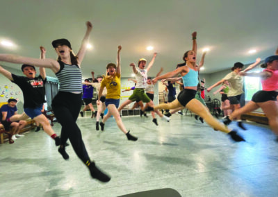 teen cast of musical, leaping during dance rehearsal