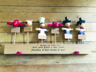 wooden skewers with simple characters such as a chef, a pig, a bull and cowboy carved at the top