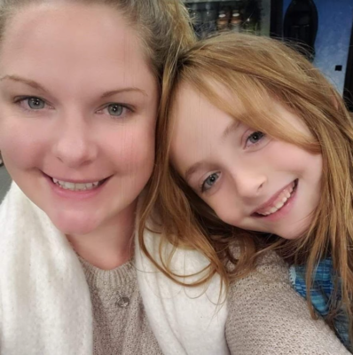 selfie of smiling young woman with young girl leaning into her shoulder and smiling