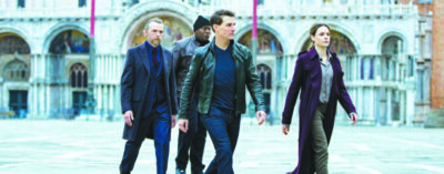 Tom Cruise and 3 other actors walking through stone courtyard in scene from Mission: Impossible — Dead Reckoning Part One