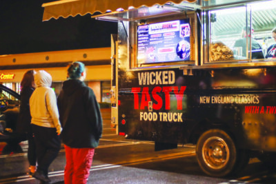 women standing in parking lot in front of good truck, nightime