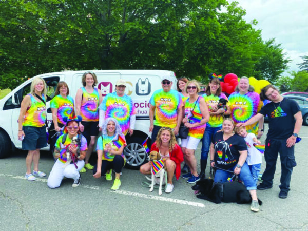 group of people, some with dogs, standing in front of van, wearing rainbow tie-die shirts