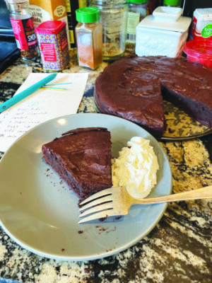 round chocolate cake with triangular piece cut out beside triangular piece on plate with scoop of vanilla ice cream