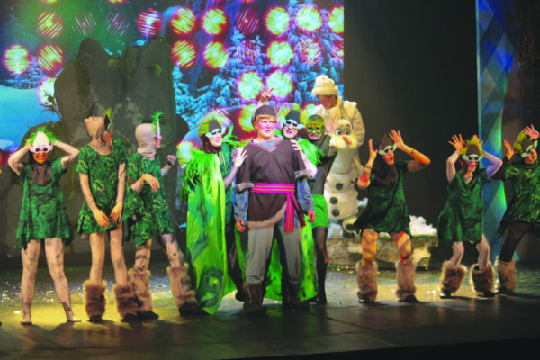 cast in troll costumes on stage, lined up to do a dance