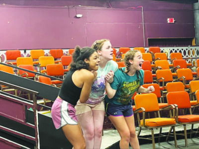 3 female actors reacting with astonishment during rehearsal in small auditorium