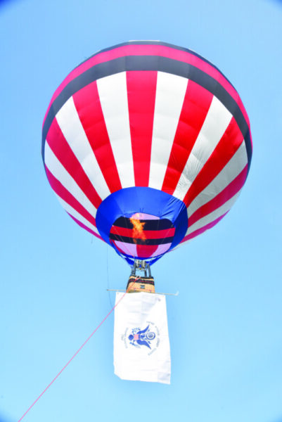 red, white and blue hot air balloon rising into blue sky