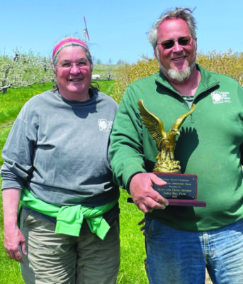 man and woman standing outside in field, man holding trophy