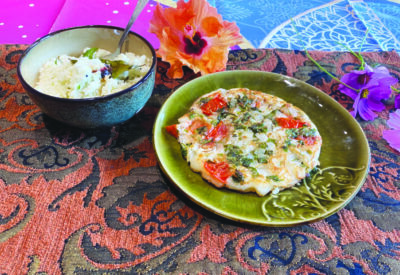 flatbread with vegetables and spices cooked into it, on plate beside bowl of coconut chutney