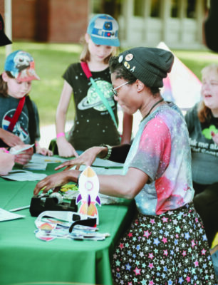 girl scouts making science projects at outdoor table at event