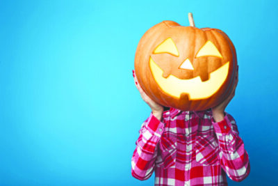 Female hands holding halloween pumpkin on blue background