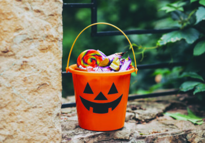 Halloween Jack o Lantern orange bucket with candy treats outdoor.