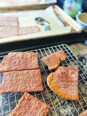 homemade graham crackers on cooling rack beside baking tray
