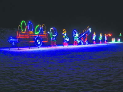 lit Christmas decorations of elves loading presents into sleigh