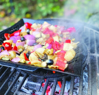 cooking tray with chopped vegetables sitting on grill, smoke rising