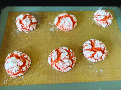 six cookies, bright color inside, covered in powdered sugar, one baking sheet