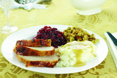Thanksgiving turkey dinner with mashed potatoes and gravy, stuffing, and homemade cranberry sauce.