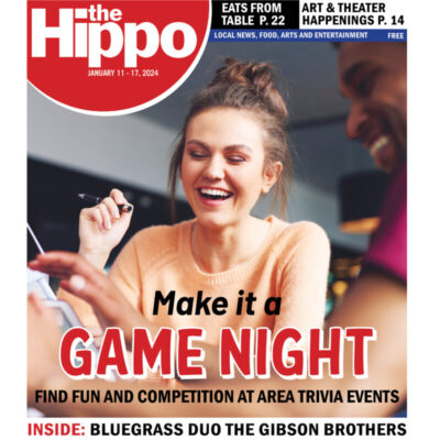 cover of hippo showing woman with pen at table in public space, laughing with friends, title Make it a game night