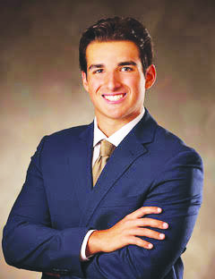 Young man smiling dressed in a blue suit.