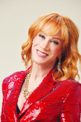 headshot of middle aged red haired woman, wearing red sequined jacket, smiling