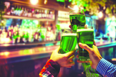St. Patrick's Day celebration promotion at a local bar or pub. Human hands clinking mugs filled with green beer. Traditional holiday. Concept of holidays, celebration, events
