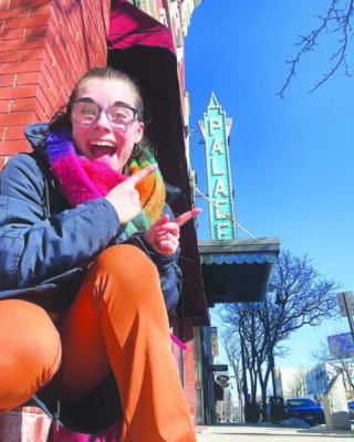 Perspective picture of a girl pointing at the Palace Theater sign in Manchester.
