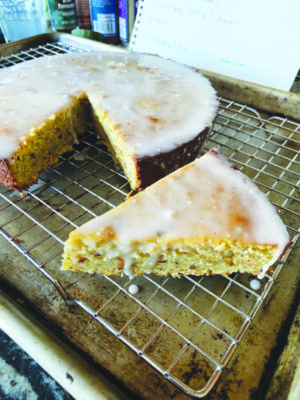 short, one layer round cake with glaze on top, sitting on cooling rack