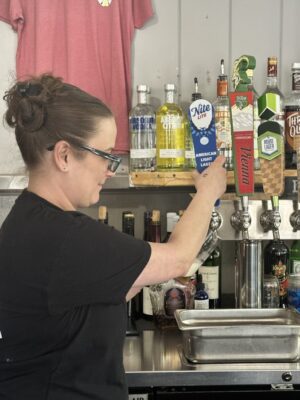 Woman at bar pouring beer from tap
