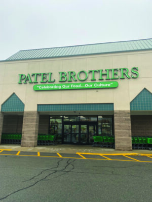 outside of large storefront with green letters reading Patel Brothers, cloudy day
