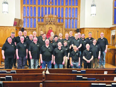 group of men wearing black shirts standing at front of church in rows, smling