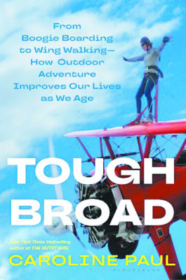 book cover with woman standing on top of vintage plane that reads "tough broad"