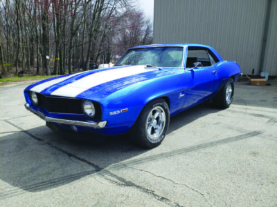 1969 Camaro sitting in a lot, painted blue with white stripes on the hood
