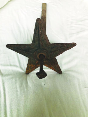 rusty metal flat star, hole in middle with bar going through it