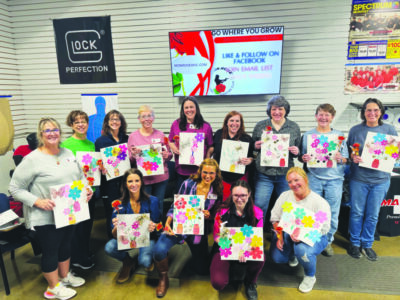 group of women posing together, holding collages of cut out colorful flowers