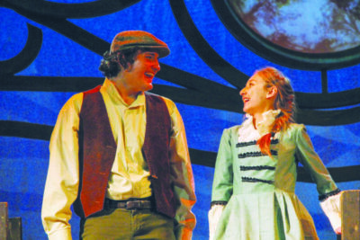 young man and young woman dressed in old fashioned clothing on stage. laughing together